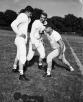 Line Coach Lon Goldstein demonstrates blocking to John Cole and Robert Spellings by Al Panzera