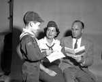 Cub Scout, Kenneth Michael Males showing handbook to Mr. and Mrs. E. A. Males