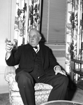 Senator Connally seated in chair, holding cigar