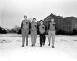 Four TCU basketball players walking through sleet covered campus