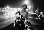 Bill Turner plays a guitar beside idle toll gates