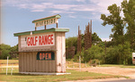 Riverside Drive-in theater converted to golf range with rotted screen in background by Milton Adams