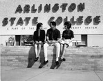 Three students sitting in front of ASC sign