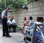 Group of students sitting on outdoor benches talking with a UTA instructor