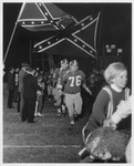 Arlington State College (A. S. C.) football players running under Rebel flags