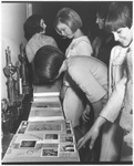 Coeds looking at photo album and scrapbooks for the San Souci club at Arlington State College (A. S. C.)