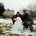 Two students with snowman posed near University of Texas at Arlington's (U. T. A.) Central Library