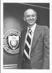 UTA President Wendell Nedderman standing beside seal