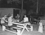 Four people eating at a picnic table by W. D. Smith