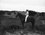 A woman in cowgirl attire sits on a horse by W. D. Smith