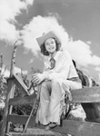 A young cowgirl sits on a fence by W. D. Smith