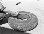 A worker fixing tire of a Hyde Corporation Trailer by W. D. Smith