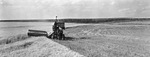 A farmer combines a field of wheet by W. D. Smith