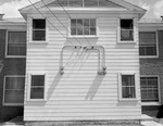 Electric lines can be seen attached on the wall of a house with five energy meters below the lines by W. D. Smith