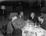 A group of men and women seated at a dining table by W. D. Smith