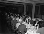 A group of men and women seated at a dining table by W. D. Smith