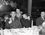 Two women and two military men pose for a photograph while seated at a dining table by W. D. Smith