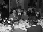 A group of men and women seated at a dining table by W. D. Smith