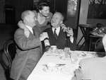 A group of men and women seated at a dining table by W. D. Smith