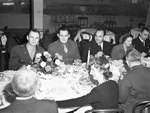 A group of men and women seated at a dining table by W. D. Smith