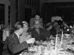 A group of men and women seated at a dining table by W. D. Smith