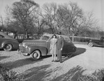 A young man and a woman stand outside in front of an automobile. The young man is wearing a military uniform by W. D. Smith