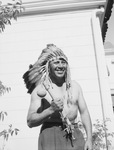 Man standing outside, wearing feather headdress by W. D. Smith