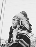 Man standing outside, wearing feather headdress by W. D. Smith