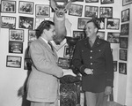 Two men standing in front of saddle, talking by W. D. Smith