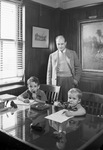 Man and two young boys sitting at a desk by W. D. Smith