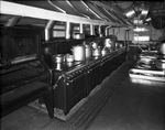 Row of stoves with various pots and pans on top by W. D. Smith