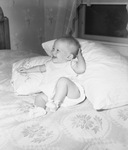 A baby girl sitting on a bed and laughing by W. D. Smith