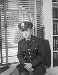 Young man in military uniform sitting on windowsill by W. D. Smith