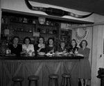 Women holding drinking glasses and standing behind a bar by W. D. Smith