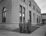 Three men standing in front of building by W. D. Smith