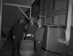 Three men standing around a barrel looking at a scoop of powdered eggs by W. D. Smith