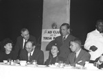 Group gathered around table with Ad Club sign in background by W. D. Smith