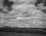 Cloudy sky with a farm house in distance by W. D. Smith