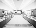 Interior of Shaw's jewelry store with aisle of jewelry counters by W. D. Smith