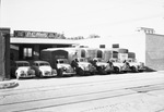 D.C. Hall Motor Transportation cars and a fleet of trucks in front of building by W. D. Smith