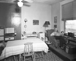 Man smoking and reading newspaper in small apartment by W. D. Smith