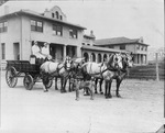 Two men sitting on horse-drawn wagon in front of Livestock Exchange Building, Fort Worth Stockyards