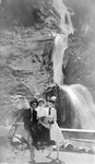 3 people on a mule near waterfall