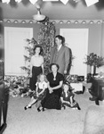 A family is posed next to their Christmas tree by W. D. Smith