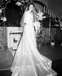 Lavenia Alexander standing by the alter in her wedding gown by W. D. Smith