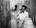 Bride and groom feeding each other pieces of wedding cake by W. D. Smith