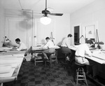 Four employees working on drafting tables in the Charlie Armstrong Offices by W. D. Smith