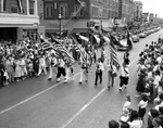 The United States and Texas flags lead the start of an All State Shrine parade by W. D. Smith