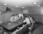 Men at a conference table looking at plans. by W. D. Smith